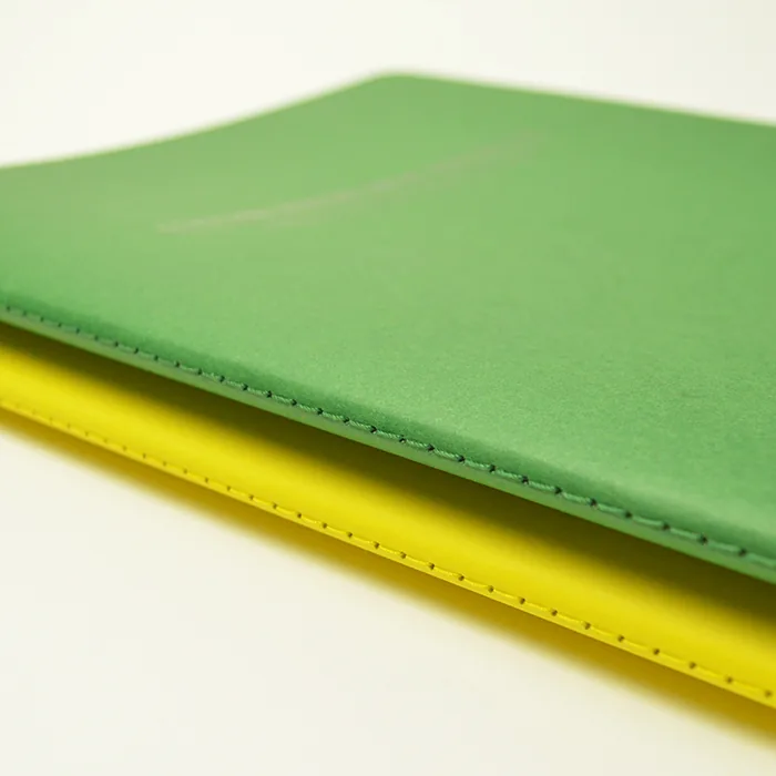 Reliure couture Singer à cheval — cahier vert et jaune, façonnage artisanal Coptos